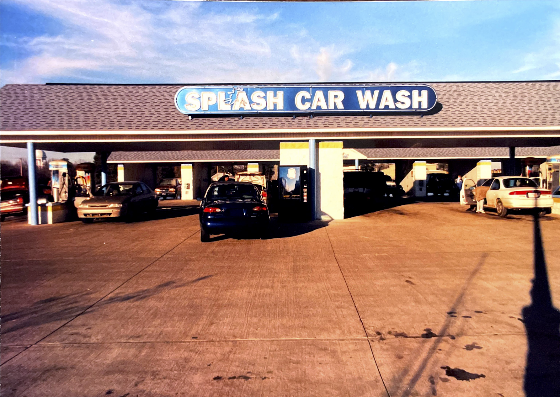 Self-serve Splash Car Wash with cars in stalls and at vacuuming stations.