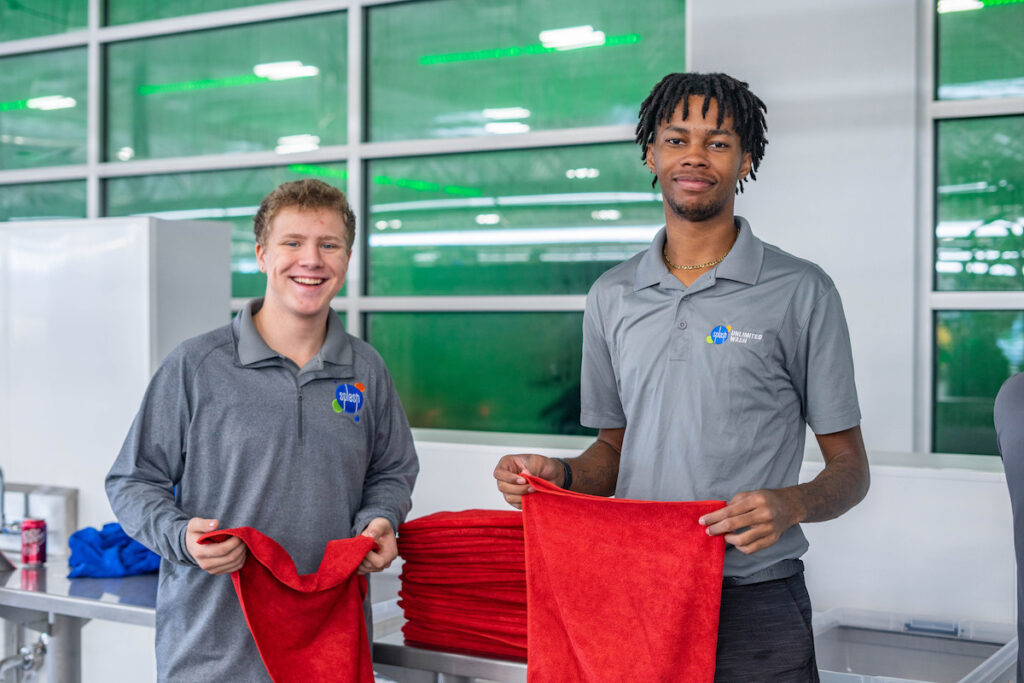 Two male Splash employees holding red towels looking at the camera and smiling.
