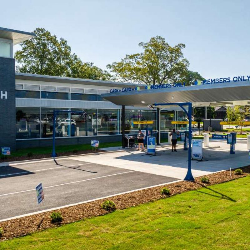 Bryant Splash Car Wash check-in area has three lanes leading to the inside of the car wash. Lanes are outside with white canopy overhead. One lane is titled "CASH & CARD" and two are "MEMBERS ONLY" and all are in blue lettering.