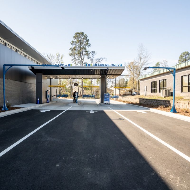 Entrance lanes for cars with individual payment kiosks. Two lines are titled "CASH + CARD," and one is titled "MEMBERS ONLY." White arrows and lines on the payment direct drivers on where to go
