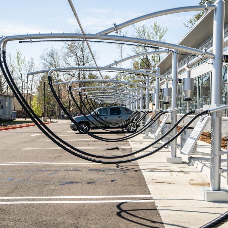 Up close view of Splash Car Wash vacuuming stations. Two back hoses run from the metal overhang of the machine. A gray truck sits in one of the vacuuming stations.
