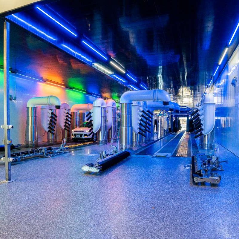 White car goes through a drying station inside the Splash Car Wash facility. Area is lit up by different colored neon lights.