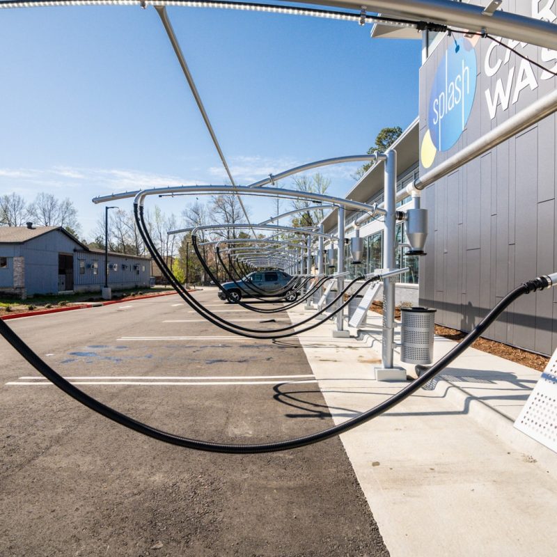 Parking lot of vacuuming stations sit next to front of Sherwood Splash Car Wash building.