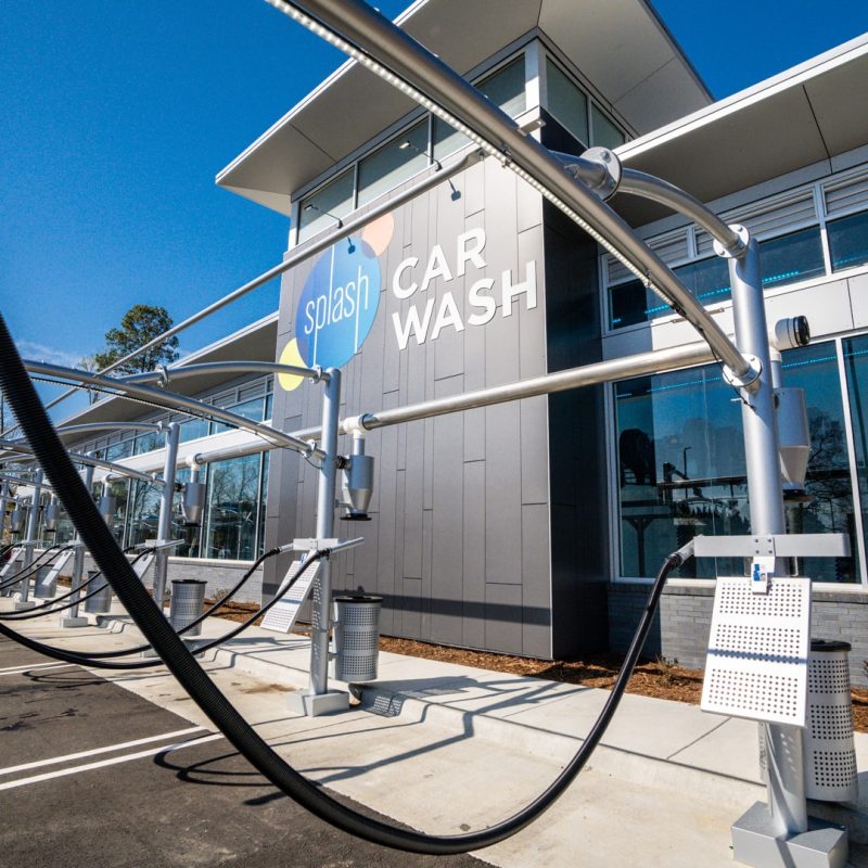 Outside view of Sherwood Splash Car Wash location. Outside vacuuming stations sit next to the front of the building with the Splash logo.