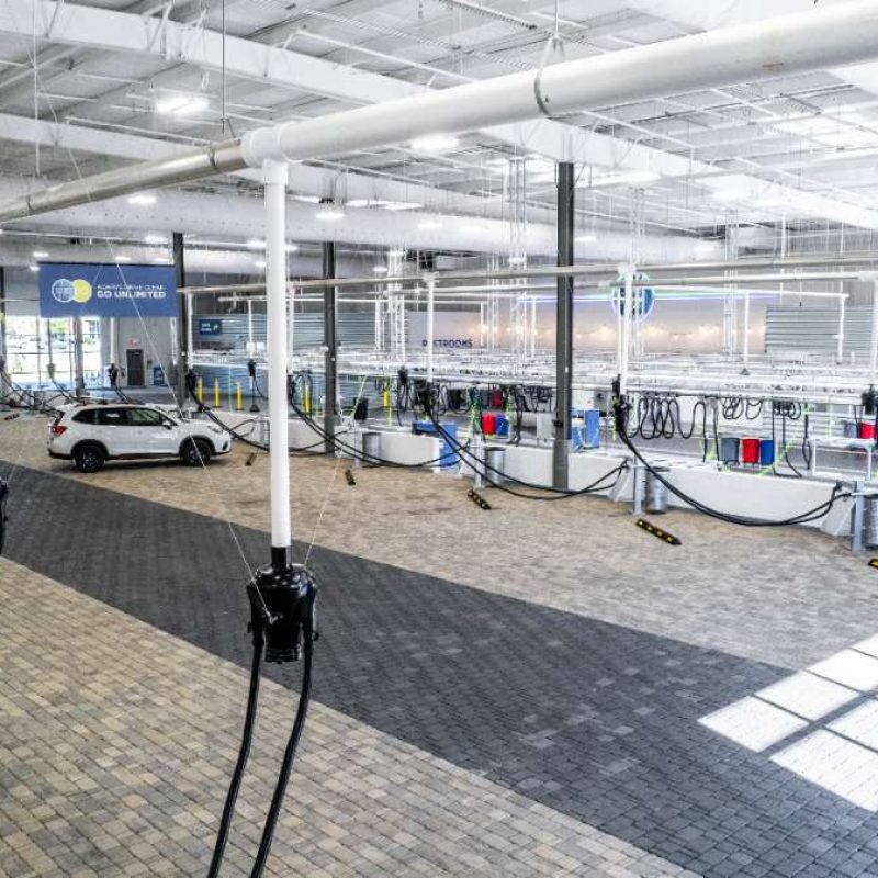 Two white cars and one black truck are parked at vacuuming stations inside the Splash Car Wash facility.