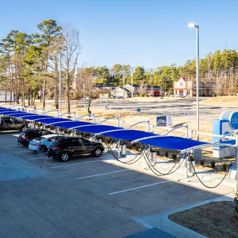 Cars parked in Splash Car Wash vacuuming station outside next to high way.